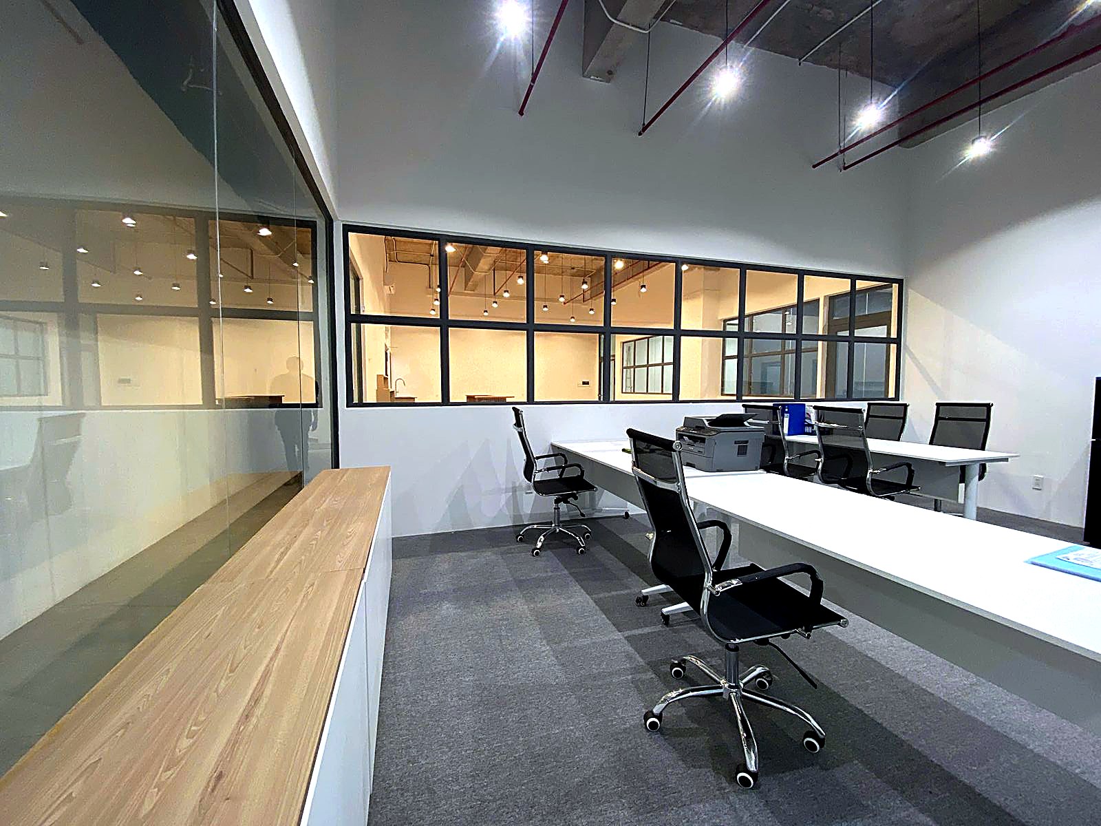 The Cargonomics office at Flexed, with white desks and black mesh chairs behind a glass partition.