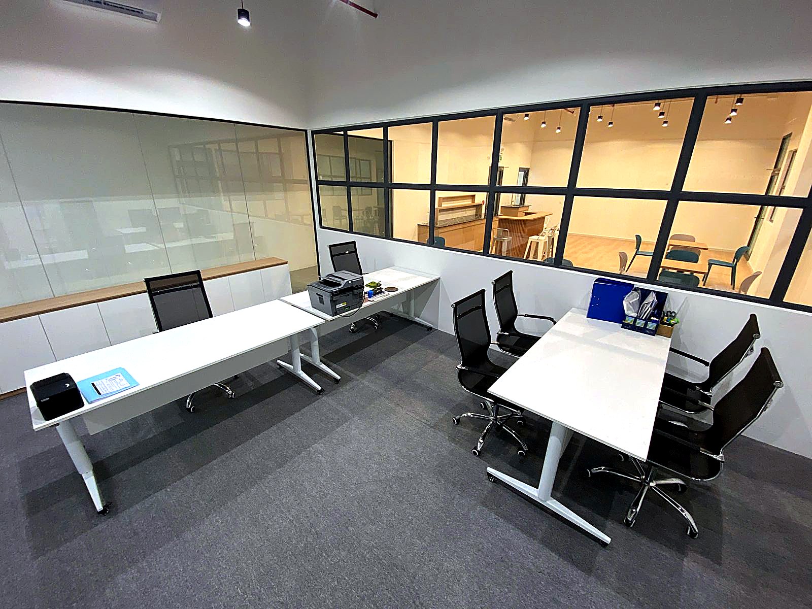 A glass-walled private office with desks and mesh chairs for a monthly team membership.