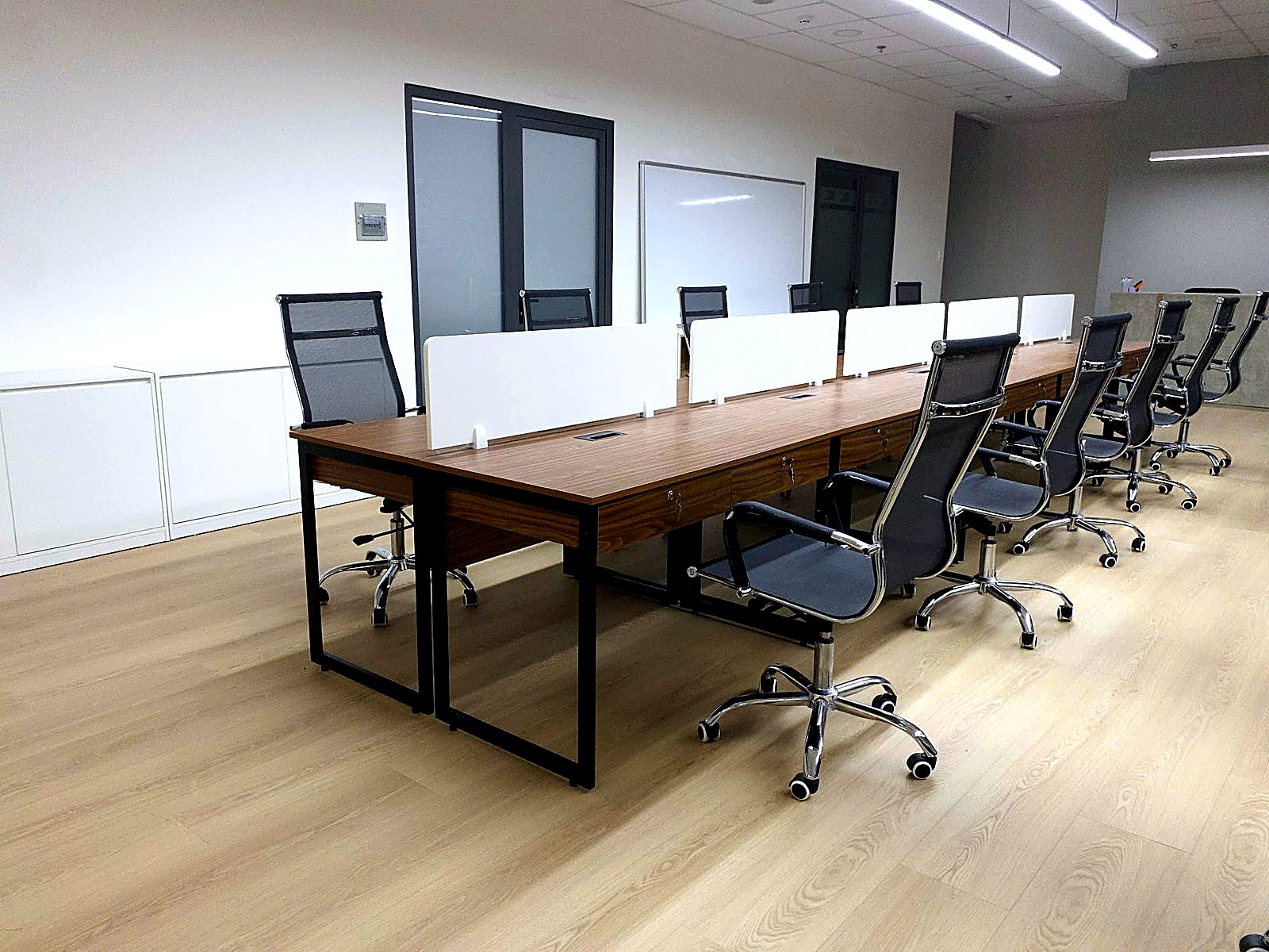 Private office with a wood meeting table, mesh chairs and white storage for a small team.